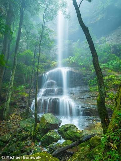 Misty waterfall cascading through lush green rainforest